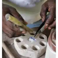 Global Mamas Bead Making Workshop pouring pounded recycled glass into mold before firing